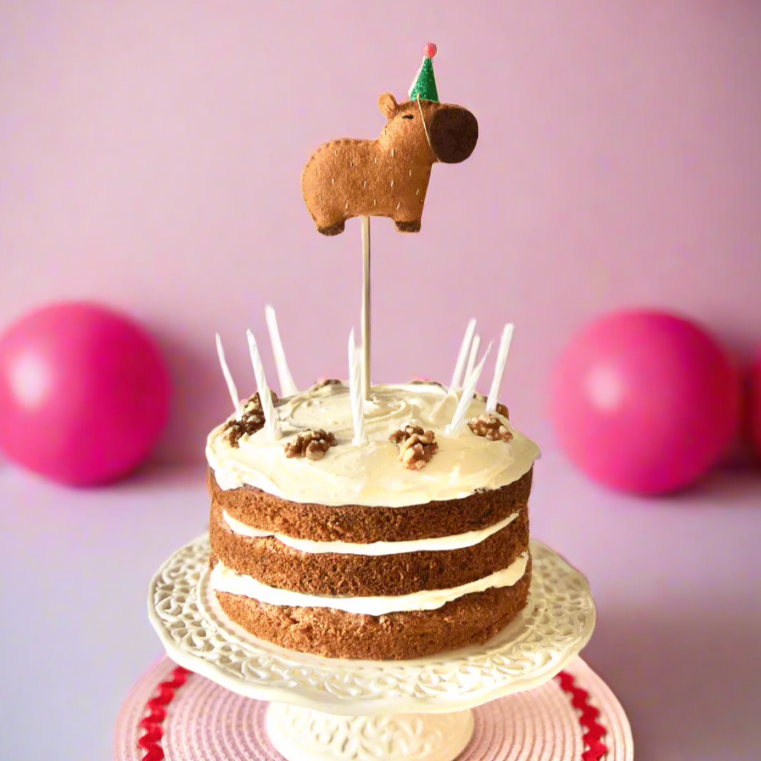 Capybara cake topper. A brown capybara wearing a party hat