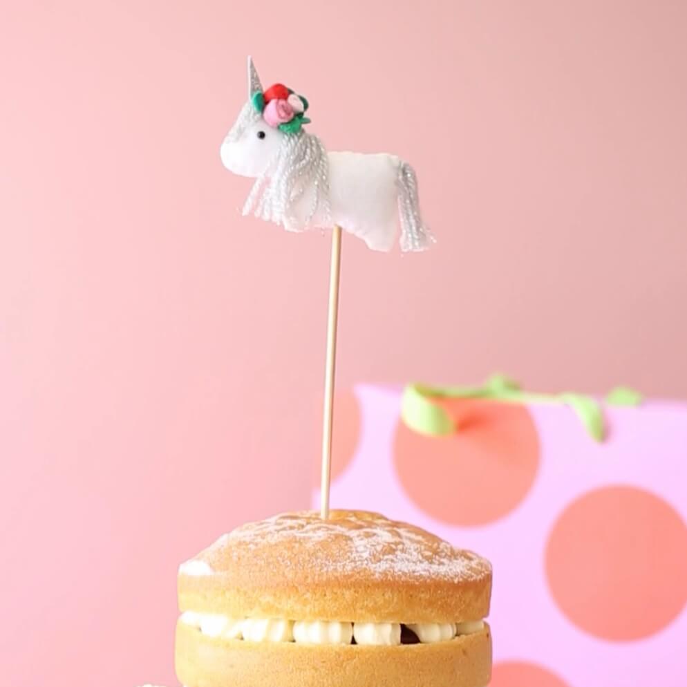 Felt unicorn birthday cake topper. The unicorn wears a flower crown.