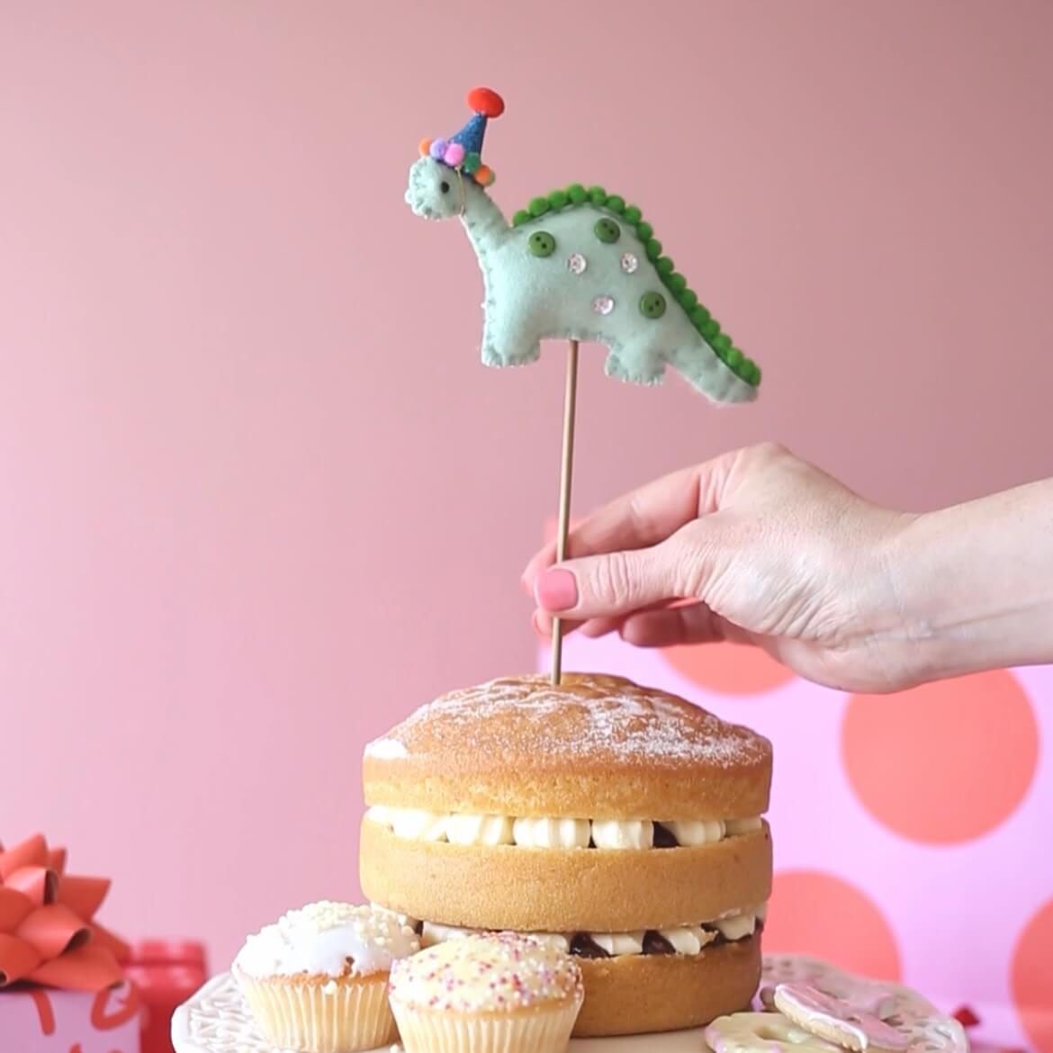 Green dinosaur birthday cake topper with a blue party hat.