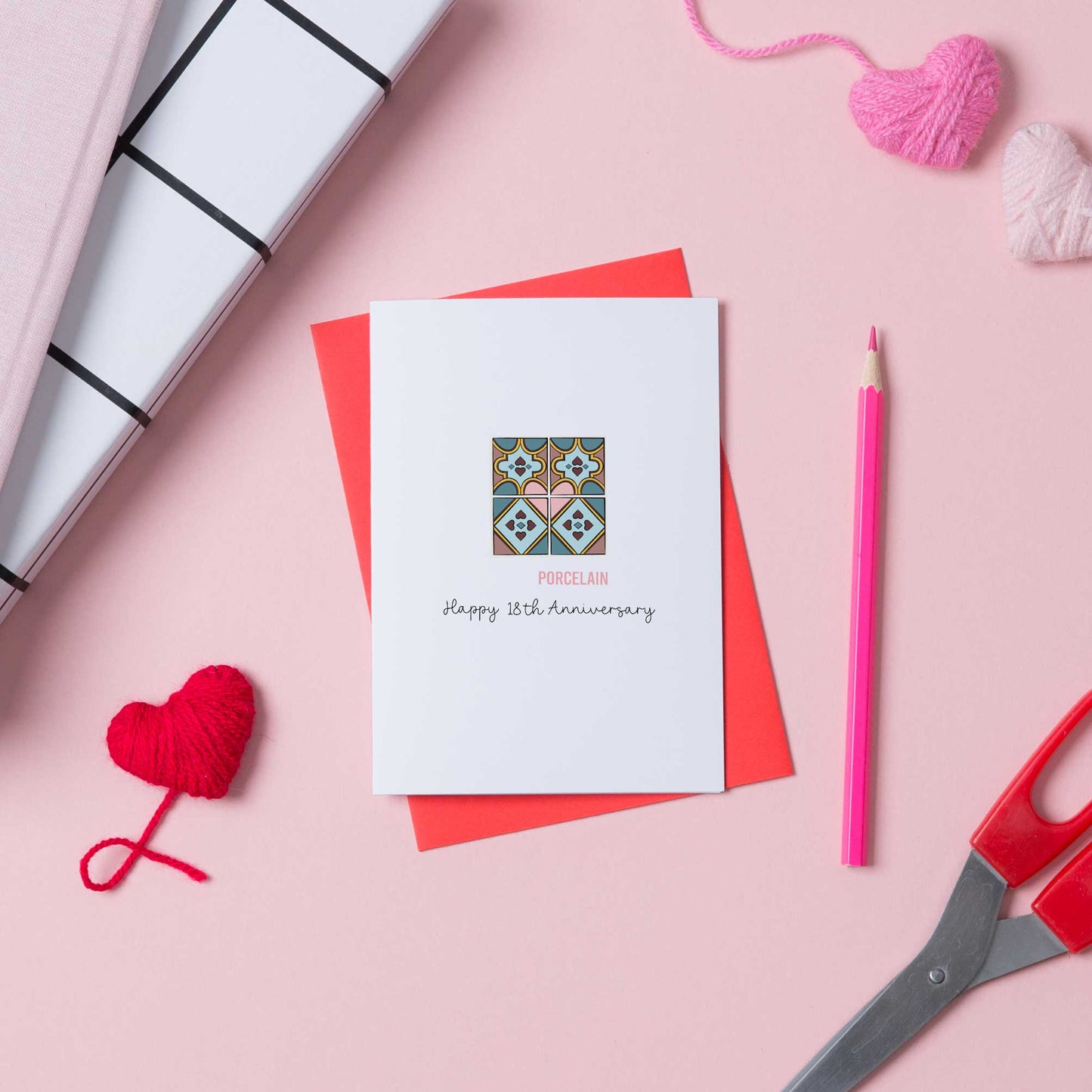 A 18th anniversary card with a picture of porcelain tiles on the front. The card us white and sits on a red envelope.