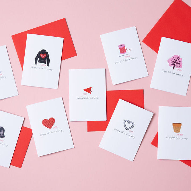 A selection of anniversary cards for each year of an anniversary based on the traditional gifts for that year. The cards are white and come with a red envelope.