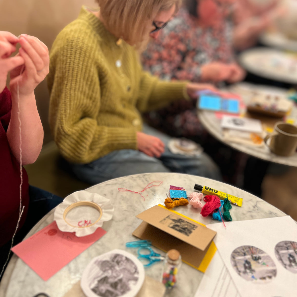 People sitting around a table with various items including a teacup, snacks, and a phone.