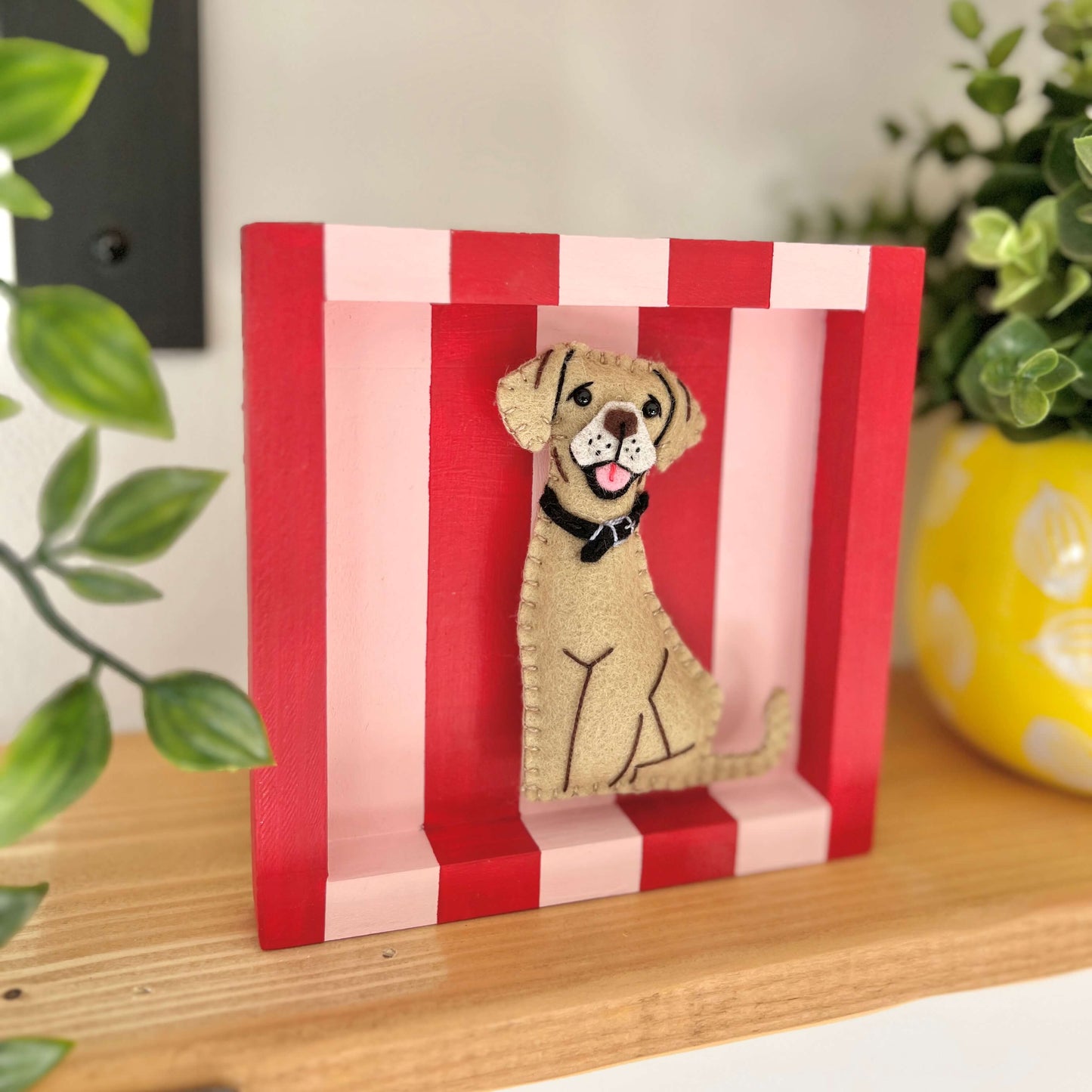 Personalised felt Pet Decoration and keepsake on a striped red and pink frame. Displayed on a shelf.