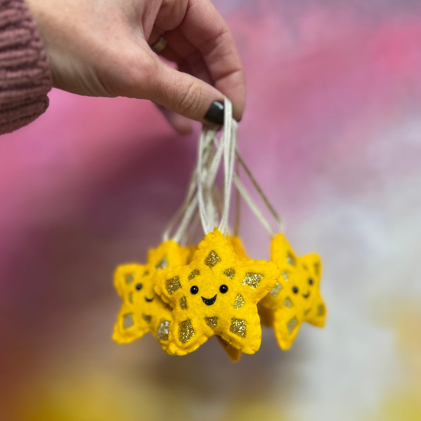 Hand holding star Christmas decorations. The stars are yellow and have happy smiley faces.