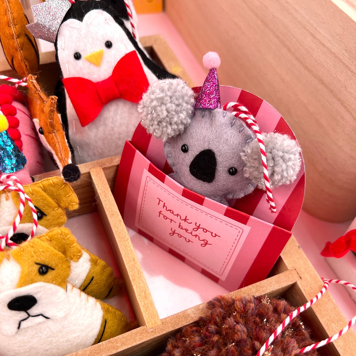 Personalised red and pink gift pocket box t for handmade felt decorations. Special message like 'Happy Birthday' or 'Thinking of you' This photo shows a handmade felt koala ornament wearing a part hat.