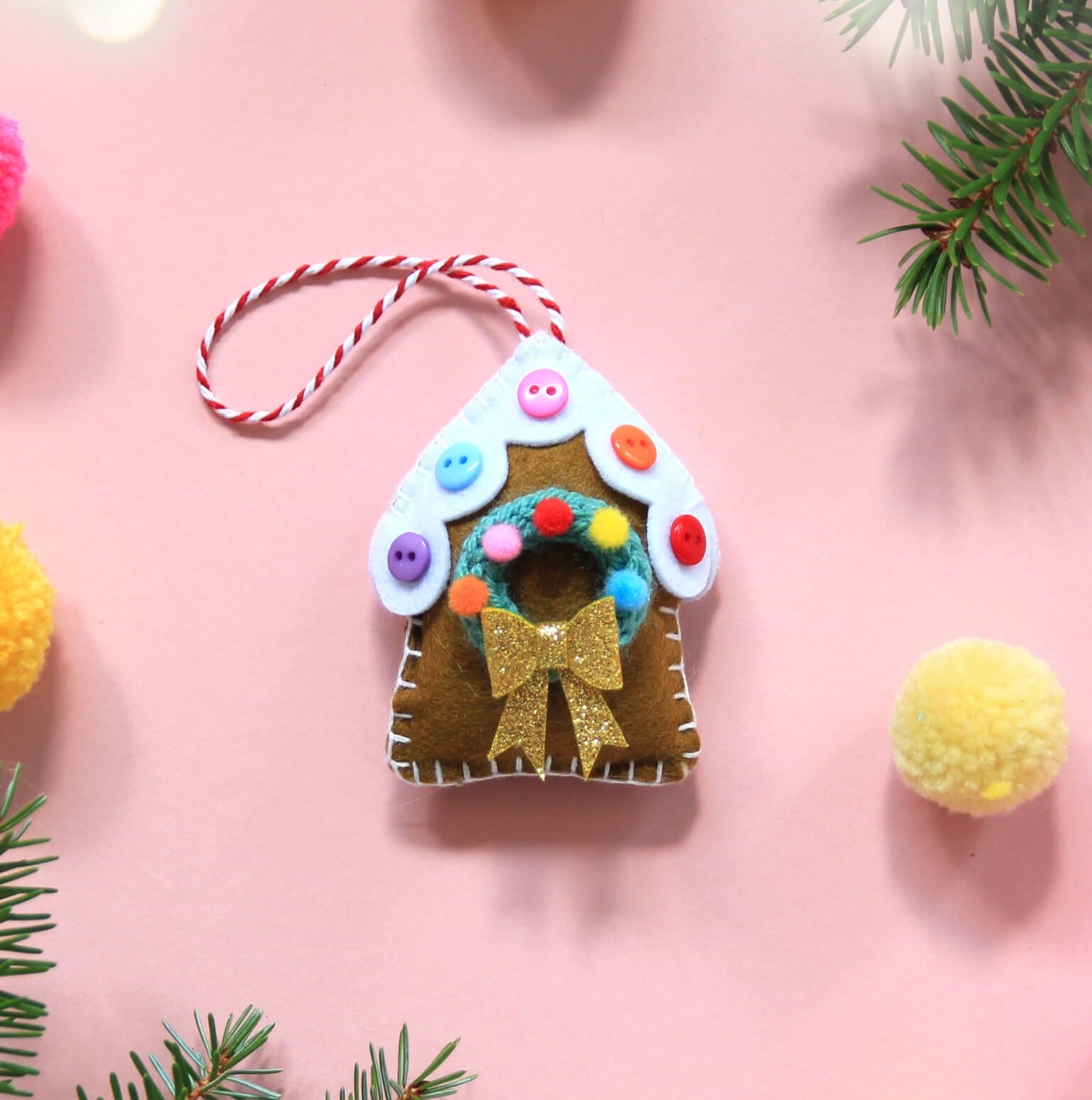 Gingerbread house decoration with mini knitted wreath, decorated with pom poms and colourful buttons.