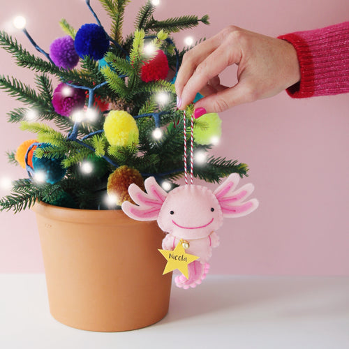 pink axolotl christnas tree decoration being hung on a Christmas tree